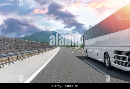 Ein weißer Touristenbus fährt auf einer Bergstraße. Stockfoto