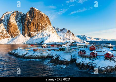 Ein winziges Dorf liegt auf einer kleinen Insel inmitten eines Wassers. Das Dorf wirkt malerisch vor dem Hintergrund der zerklüfteten Insellandschaft. Stockfoto