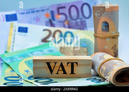 MwSt-Text auf Holzblöcken mit Euro-Banknoten als Hintergrund. Stockfoto