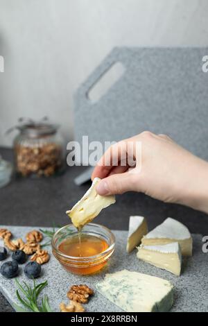 Frau hält Käse und taucht ihn in Honig Stockfoto