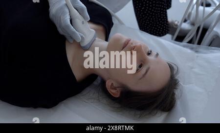 Ultraschallgerätearzt führt Schilddrüsenuntersuchung einer jungen Frau durch. Clip. Konzept von Medizin und Gesundheitsfürsorge. Stockfoto