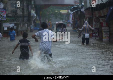 Dhaka. Mai 2024. Menschen waten durch eine wasserdurchflutete Straße in Dhaka, Bangladesch, 27. Mai 2024. Mindestens sieben Menschen starben in Bangladesch an den Verwüstungen des Wirbelsturms Remal, der in der Sonntagnacht Teile des südasiatischen Landes mit starkem Regen und starkem Wind verwüstete. Quelle: Xinhua/Alamy Live News Stockfoto