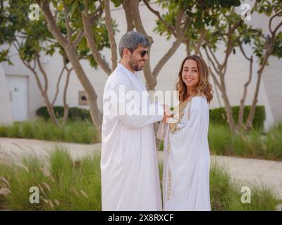 Reisen Sie in die Vereinigten Arabischen Emirate, Abu Dhabi. Arabisches Paar besucht den Park in der Nähe der Großen Moschee in Abu Dhabi in traditioneller Kleidung. Stockfoto
