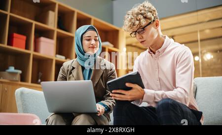 Porträt zweier kreativer Kollegen, die im Büro mit Laptop und Tablet über die Arbeit sprechen. Young White Männlich Marketing Praktikantin Consulting Weibliche Kaukasische Kreativdirektorin. Stockfoto