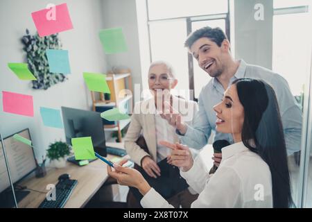 Foto von drei Geschäftsmitarbeitern, die über Punkte sprechen, die am Arbeitsplatz zu sehen sind Stockfoto