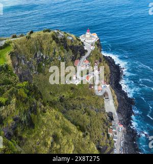 Aus der Vogelperspektive einer kurvigen Straße, die zu einem Leuchtturm auf den Azoren führt (Farol da Ponta do Arnel ) Stockfoto