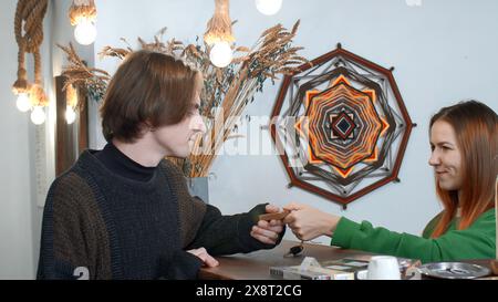 Der Hotelmanager gibt den Schlüssel zum Hotelzimmer an der Rezeption. Medien. Weibliche Rezeptionistin gibt einem männlichen Besucher im Ethno einen altmodischen Schlüssel Stockfoto