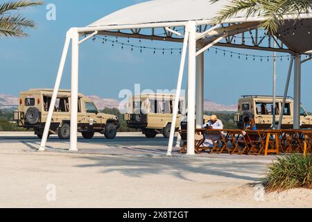 Sir Bani Yas, VAE - 5. Januar 2024: Touristen bereiten sich auf eine Safari unter einem Baldachin mit geparkten Geländefahrzeugen im Hintergrund vor. Stockfoto