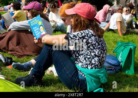 Junge Frau, die vor dem Buchladen des Hay Festivals auf dem Rasen sitzt und Anne Enright Buch „The Wren the Wren“ liest, Wales UK KATHY DEWITT Stockfoto