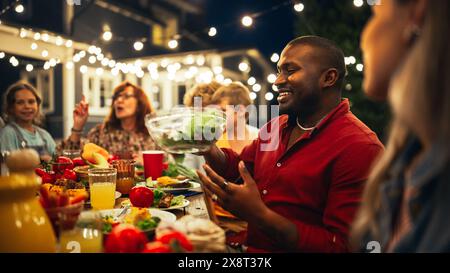 Big Family Garden Barbecue Party Celebration, versammelt an einem Tisch mit Verwandten und Freunden. Junge und Senioren essen, trinken, Essen gehen, scherzen und haben Spaß. Stockfoto