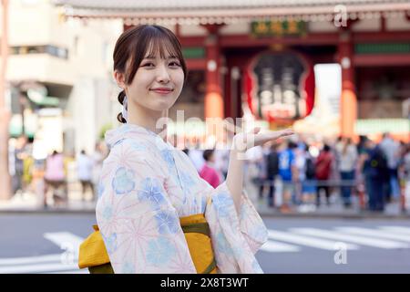 Japanische Frau in einem Yukata, die den traditionellen Tempel in Tokio besucht Stockfoto