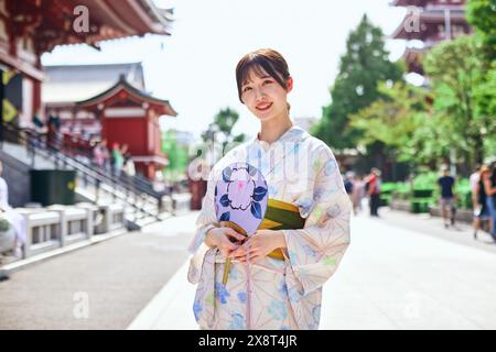 Japanische Frau in einem Yukata, die den traditionellen Tempel in Tokio besucht Stockfoto