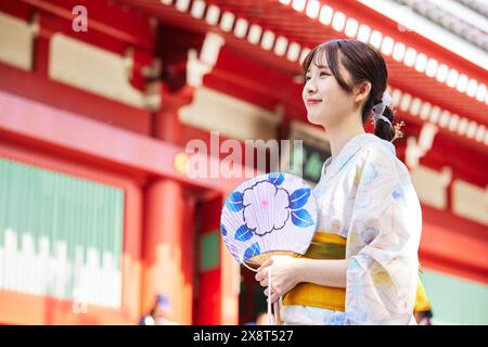 Japanische Frau in einem Yukata, die den traditionellen Tempel in Tokio besucht Stockfoto