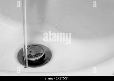 Detail mit weißem Keramikwaschbecken in modernem Bad mit Chromabfluss und Leitungswasser. Horizontal. Für Text. Stockfoto