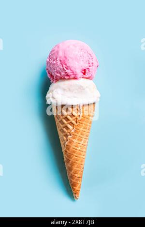 Schaufel Vanille- und Erdbeereis in Waffelkegel auf hellblauem Hintergrund, Draufsicht. Trendige kreative Vorlage. Stockfoto