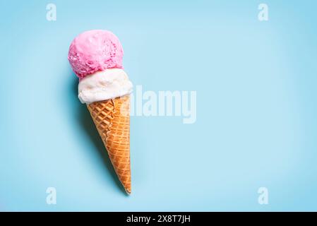 Schaufel Vanille- und Erdbeereis in Waffelkegel auf hellblauem Hintergrund, Draufsicht, Kopierraum. Trendige kreative Vorlage. Stockfoto