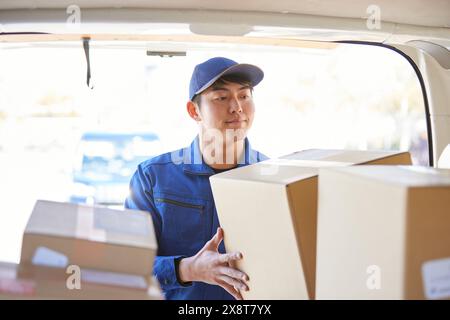 Der japanische Liefermann checkt die Kästchen im Auto Stockfoto