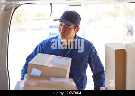 Der japanische Liefermann checkt die Kästchen im Auto Stockfoto