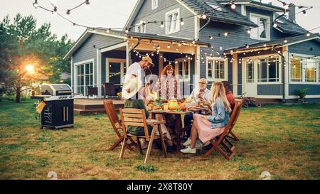 Big Family Garden Barbecue Party Celebration, versammelt an einem Tisch mit Verwandten und Freunden. Junge und Senioren essen, trinken, Essen gehen, scherzen und haben Spaß. Stockfoto