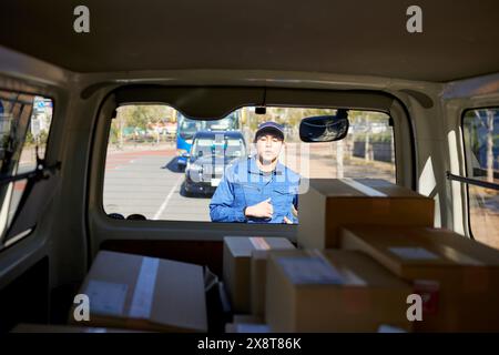 Der japanische Liefermann checkt die Kästchen im Auto Stockfoto