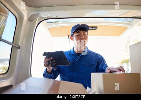 Der japanische Liefermann checkt die Kästchen im Auto Stockfoto