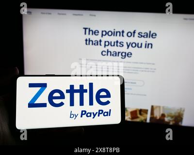 Person mit Smartphone und Logo des schwedischen Fintech-Unternehmens Zettle by PayPal vor der Website. Schwerpunkt auf dem Display des Telefons. Stockfoto