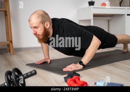 Junger athletischer Mann, der zu Hause Sport macht. Führt Plank-Übungen durch. Kopierbereich Stockfoto