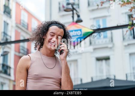 Schwule Person in femininer Kleidung, die auf dem Smartphone spricht Stockfoto