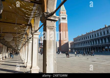 Markusplatz mit Bogengang und dem berühmten Glockenturm an einem sonnigen Tag mit blauem Himmel in Venedig, Venetien, Italien Stockfoto