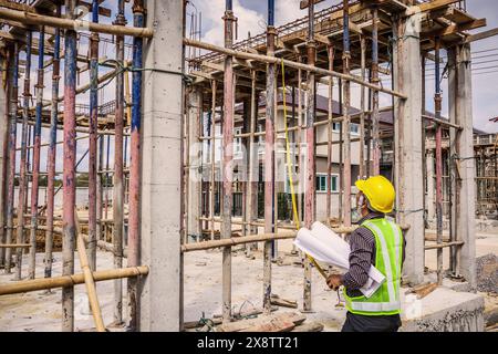 Asiatischer Bauingenieur in Schutzhelm und Bauplanpapier auf der Baustelle Stockfoto