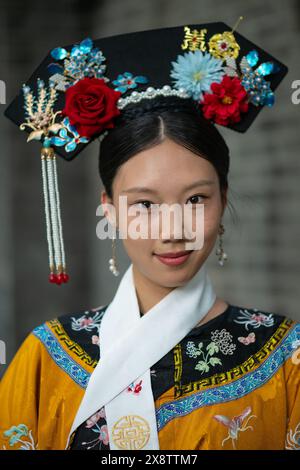 Zwei junge Frauen in leuchtenden gelben und blauen traditionellen Hofkostümen der Qing-Dynastie posieren im Freien in Peking, China. Stockfoto