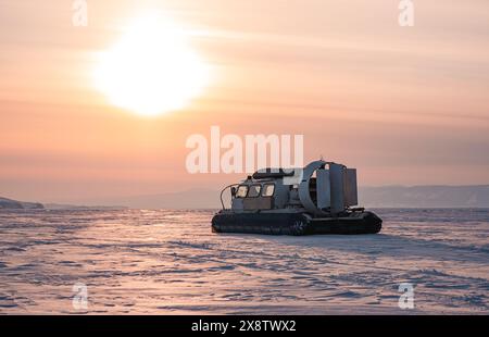 Hovercraft stehen auf schneebedeckter Eisfläche des Baikalsees in der Abenddämmerung. Stockfoto