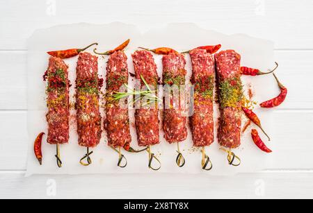 Roher Kebab mit Gewürzen auf einem weißen Tisch Stockfoto