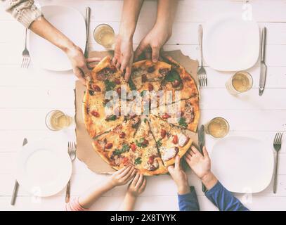 Vier Hände, die Pizzastücke von oben nehmen Stockfoto
