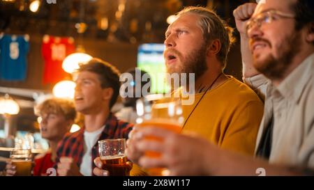 Gruppe guter Freunde, die ihre Zeit in einem Sports Pub genießen. Drei Männer jubeln ihr Lieblingsfußballteam an. Junge Leute feiern und tosten Biergläser, wenn Spieler ein Tor schießen und gewinnen. Stockfoto