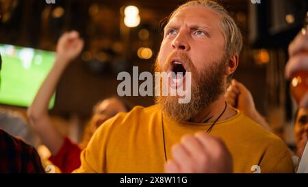 Gruppe von Fußballfans, die ein Live-Fußballspiel in einer Sportbar anschauen. Drei männliche Freunde stehen vor einem Fernseher, stoßen Biergläser an und feiern das Tor und den Meisterschaftsgewinn. Stockfoto