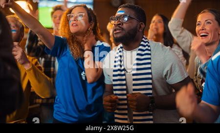 Verschiedene Fußballfans sehen sich eine Live-Übertragung von Fußballspielen in einem Sports Pub im Fernsehen an. Die Leute Jubeln Und Unterstützen Ihr Team. Die Zuschauer sind begeistert, wenn das Team ein Tor erzielt und die Meisterschaft gewinnt. Stockfoto