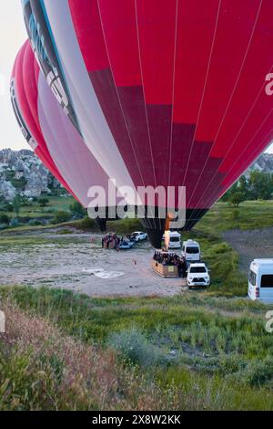 Ein beeindruckender Heißluftballon gleitet über das zerklüftete Gelände von Kappadokien, Türkei, unter einem hellblauen Himmel. Das Bild fängt das Wesen des Abenteuers ein Stockfoto