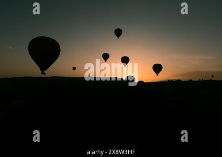 Heißluftballons bilden eine Silhouette vor dem Morgenhimmel in Kappadokien und schaffen eine ruhige und fesselnde Szene. Die Ballons schweben anmutig über die rugge Stockfoto