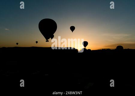 Heißluftballons bilden eine Silhouette vor dem Morgenhimmel in Kappadokien und schaffen eine ruhige und fesselnde Szene. Die Ballons schweben anmutig über die rugge Stockfoto