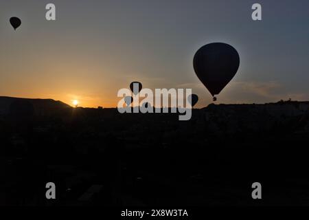 Heißluftballons bilden eine Silhouette vor dem Morgenhimmel in Kappadokien und schaffen eine ruhige und fesselnde Szene. Die Ballons schweben anmutig über die rugge Stockfoto