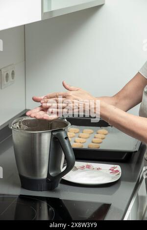 Mehl über einem Küchenmixer mit Keksteig bestäuben, um die Backzubereitung auf einem modernen Herd anzuzeigen Stockfoto