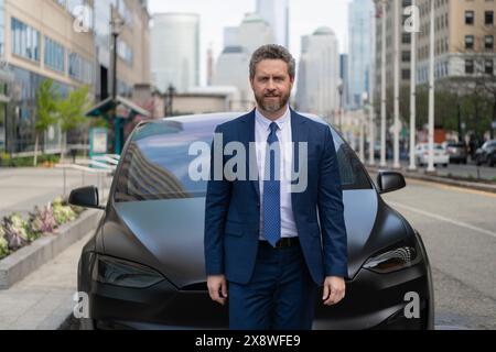 Versicherungsvertreter bei Luxuswagen. Erfolgreicher Autohändler. Autohändler Kfz-Versicherung. Geschäftsmann Händler im Freien. Dealer Mann im teuren Anzug. Stockfoto