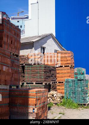 Verkauf von Baumaterialien auf der Straße. Freiluftmarkt für Baustoffe. Ein Haufen Ziegeln in Schläfern. Konzept der Bauvorbereitung Stockfoto