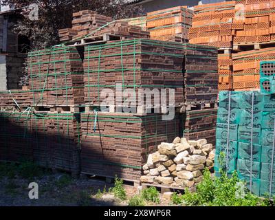 Verkauf von Baumaterialien auf der Straße. Freiluftmarkt für Baustoffe. Ein Haufen Ziegeln in Schläfern. Konzept der Bauvorbereitung Stockfoto