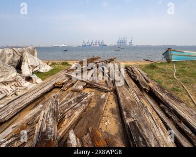 Felixstowe Containerpunkt von Harwich aus gesehen mit gestapeltem Holz und heruntergekommenen Booten im Vordergrund. Stockfoto