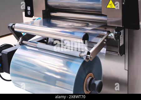 Automatische Polyethylen-Plastiktüten-Produktionsmaschine mit Lichteffekt. Nahaufnahme der Rolle der Produktionsmaschine für Kunststoffbeutel im Licht Stockfoto