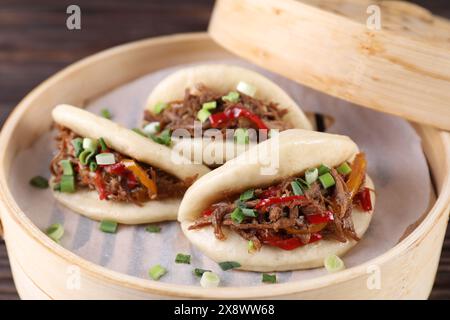 Leckere Gua bao (Schweinebauchbrötchen) in Bambusdampfer auf dem Tisch, Nahaufnahme Stockfoto