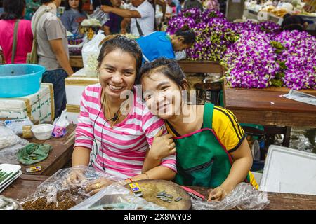 Zwei lächelnde, freundliche junge Frauen arbeiten in der lebhaften Yodpiman Flower City, einem Blumengroßmarkt in Bangkok, Thailand Stockfoto