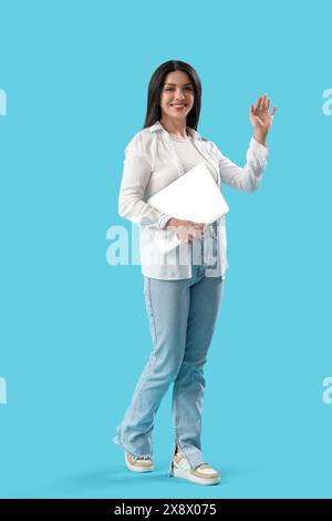Weibliches Programmiergerät mit schwenkender Hand auf blauem Hintergrund Stockfoto